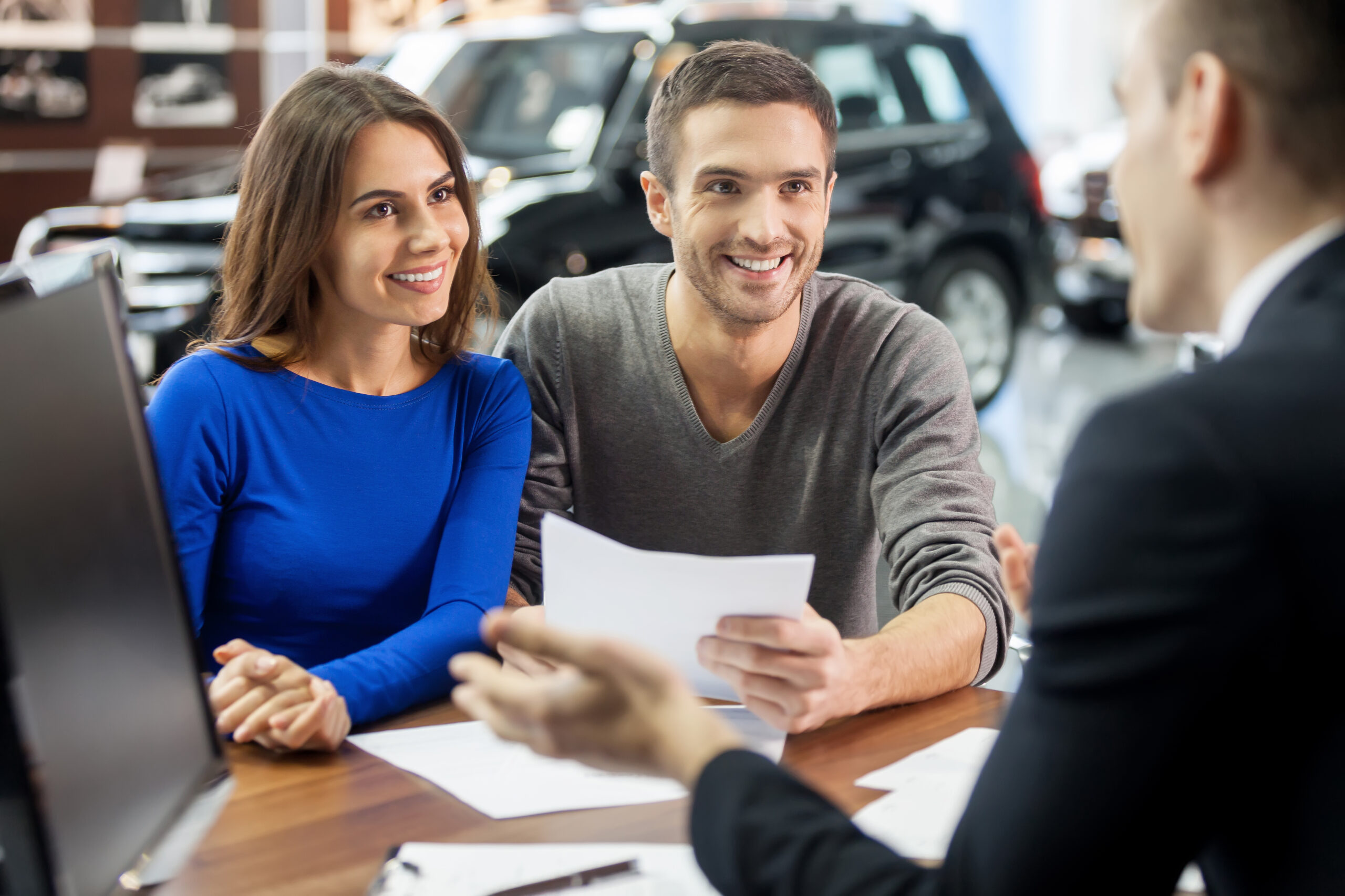 This is good choice. Confident young salesman explaining all the car features to the young attractive owners