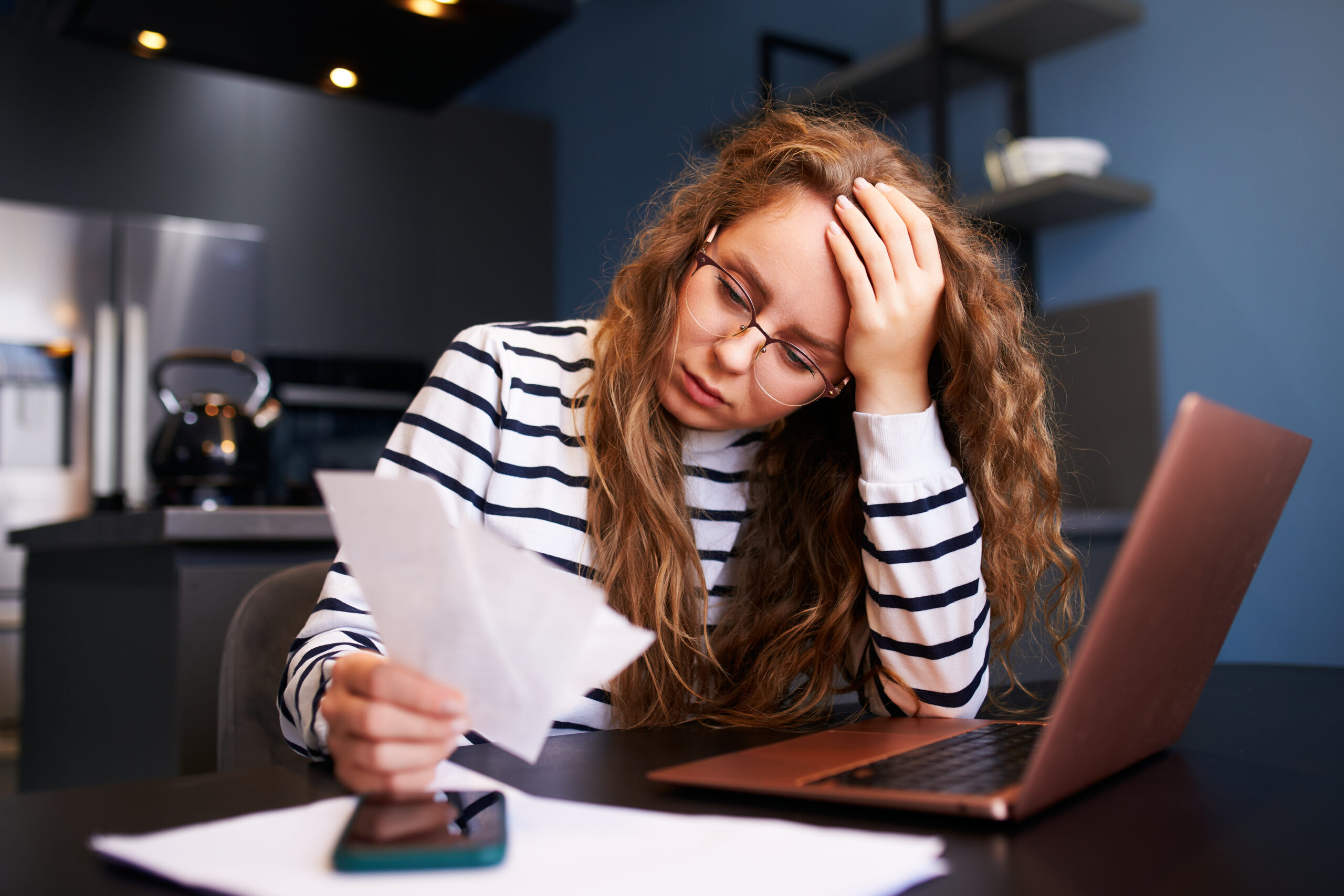 Unhappy woman calculates expenses on bills, upset about increased utilities prices. Female counting paychecks, debts, loans, reciepts to pay taxes. Inflation, financial crisis, low paying capacity.